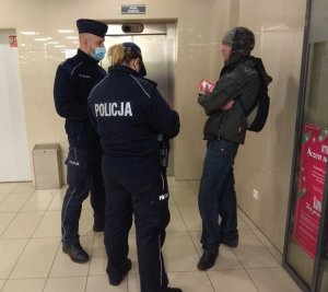 dwoje policjantów podczas legitymowania osoby w galerii