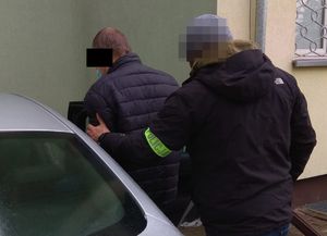 policjant prowadzi zatrzymanego