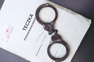 teczka z aktami sprawy, na niej leżące kajdanki