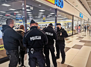 Policjanci kontrolują osoby bez maseczek zakrywających usta i nos w galerii handlowej