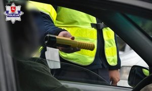 policjant ruchu drogowego sprawdzający stan trzeźwości kierowcy urządzeniem alcoblow