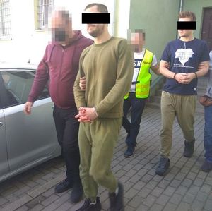 policjanci w kajdankach prowadzeni przez policjantów