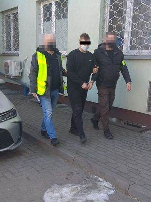 policjanci doprowadzają zatrzymanego