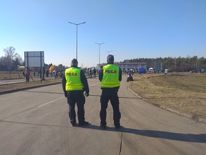 dwaj funkcjonariusze stojący za protestującymi
