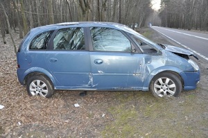 uszkodzony samochód stojący na poboczu. Za nim w tle dwa radiowozy policyjne