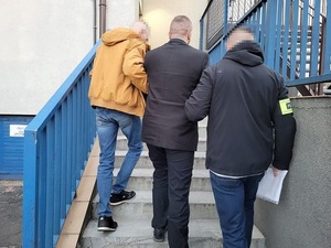 dwaj nieumundurowani policjanci prowadzą zatrzymanego 26-latka