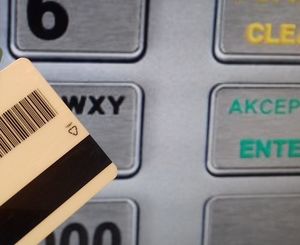 fragment karty płatniczej na tle klawiatury bankomatu