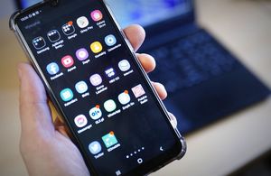 telefon komórkowy trzymany w ręku. Na wyświetlaczu widoczne ikony