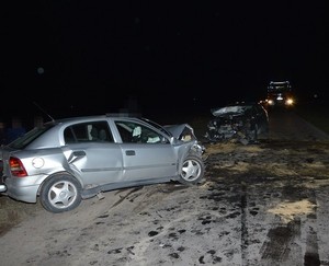 dwa uszkodzone samochody stojące na jezdni. W tle wóz straży pożarnej