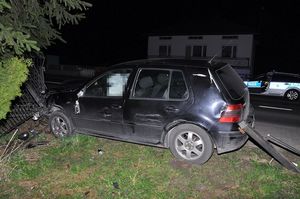 uszkodzony samochód stojący w bramie. W tle radiowóz.