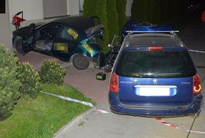 dwa uszkodzone samochody stojące przy ścianie budynku