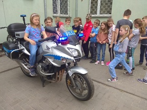 dziecko siedzące na motocyklu. obok inne dzieci