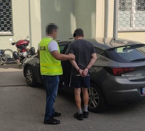 policjant doprowadza zatrzymanego