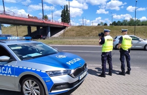dwaj policjanci ruchu drogowego stojący przy radiowozie