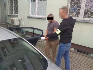 policjant doprowadza zatrzymanego