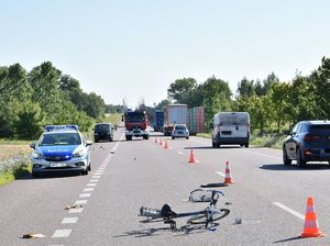 rower leżący na ulicy. Radiowóz po lewej stronie. Po drugiej stronie kolumna samochód