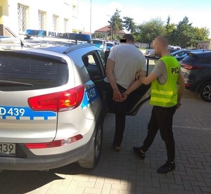 policjant wprowadza zatrzymanego