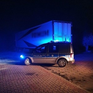 oznakowany radiowóz, za nim zaparkowany samochód cieżarowy