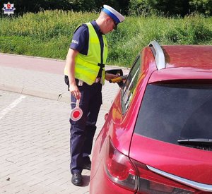 policjant przy samochodzie
policjant podaje alkometr kierowcy
dwóch policjantów jadących na motorach
policjant podczas kontroli pojazdu