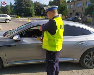 policjant przy samochodzie
policjant podaje alkometr kierowcy
dwóch policjantów jadących na motorach
policjant podczas kontroli pojazdu