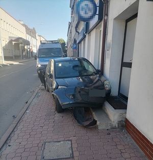 uszkodzony samochód osobowy, który uderzył w budynek. Za nim radiowóz
