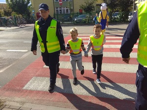 policjantka przeprowadza dzieci przez przejście