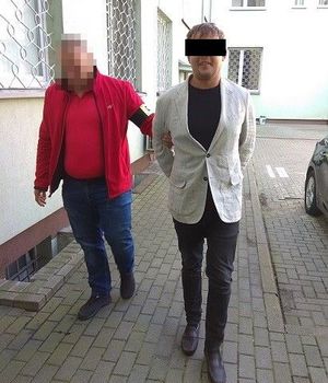 Policjant doprowadza zatrzymanego