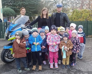 policjant na zdjęciu grupowym z przedszkolakami i wychowawczyniami.