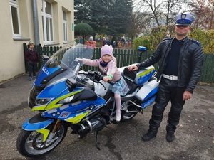 dziecko siedzące na motocyklu obok stoi policjant