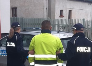 policjanci doprowadzają zatrzymanego