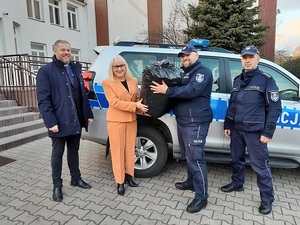 policjanci oraz kapelan przekazują worek z nakrętkami pani dyrektor.