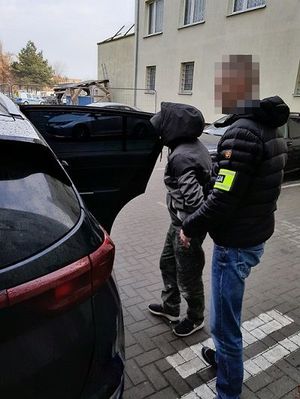 policjant doprowadza zatrzymanego