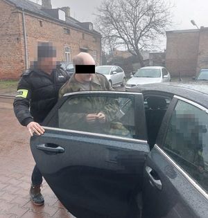 policjant doprowadza zatrzymanego