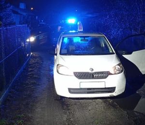 odzyskany samochód. W tle radiowóz z włączonymi sygnałami świetlnymi