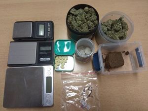 zabezpieczone narkotyki w pojemnikach plastikowych. Obok wagi elektroniczne