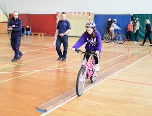 uczestniczka na torze rowerowym. Obok policjanci oceniający przejazd.