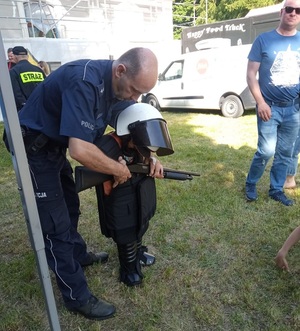 policjant pomaga dziecku przymierzyć elementy umundurowania
