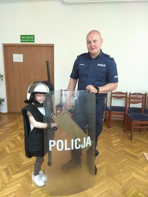 policjant z dzieckiem przymierzającym umundurowanie