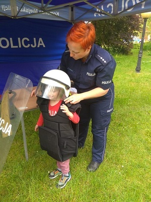 policjantka ubiera dziecko w umundurowanie
