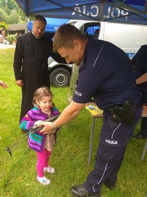 policjant pokazuje dziecku elementy umundurowania i uzbrojenia.