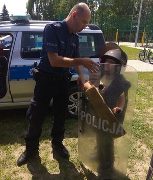 policjant pomaga dziecku założyć elementy umundurowania