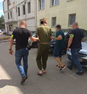 policjanci doprowadzają zatrzymanego