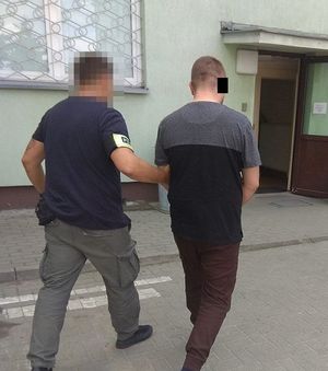 policjant doprowadza zatrzymanego