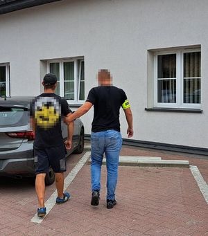 policjant doprowadza zatrzymanego