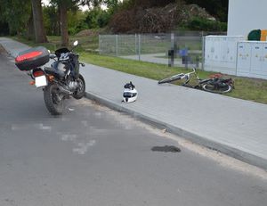 miejsce zderzenia jednośladów. Motocykl stojący na ulicy obok na trawniku leży rower.
