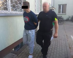 policjant doprowadza zatrzymanego mężczyznę