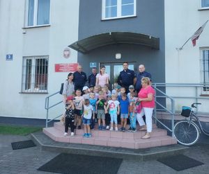 zdjęcie grupowe dzieci wraz z policjantami przed budynkiem komisariatu