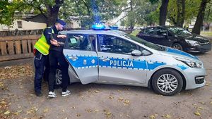 policjant wprowadza zatrzymanego mężczyznę do radiowozu