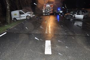 miejsce wypadku. Dwa uszkodzone samochody stojące po przeciwnych stronach ulicy. W tle służby ratunkowe