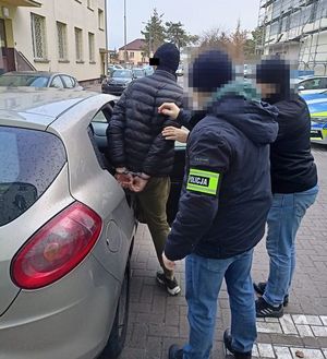 policjanci doprowadzają zatrzymanego